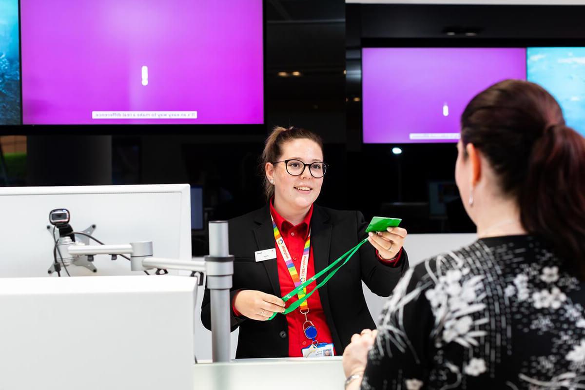 Female reception staff handing a guest pass to a visitor